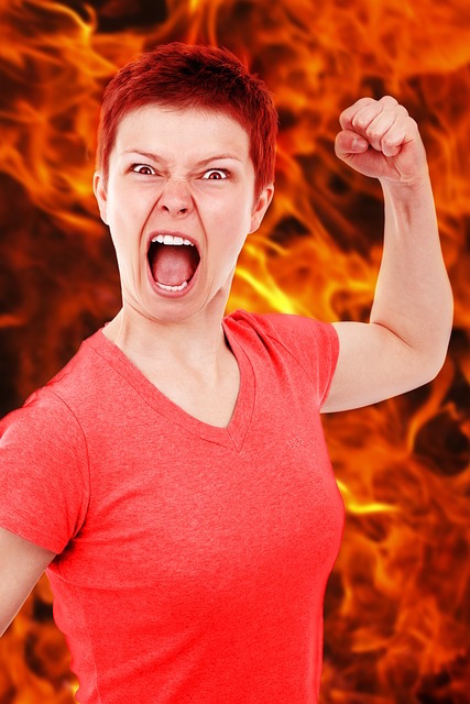 Screaming woman raising her fist in anger with fire in the background. 